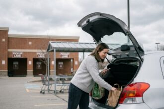 Femme chargeant ses courses drive dans le coffre de sa voiture dans un parking de supermarché
